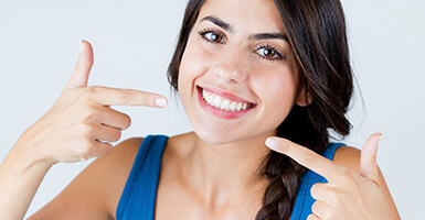 Young lady pointing to her bright smile