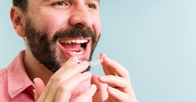 Man in pink shirt about to put in clear aligner