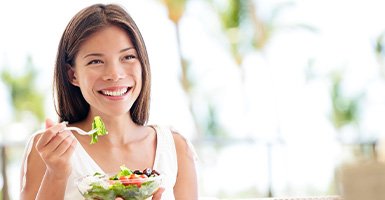 Woman sitting on a couch eating a salad