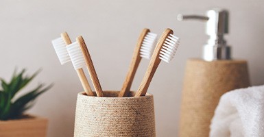 Four toothbrushes in a cup on a bathroom counter