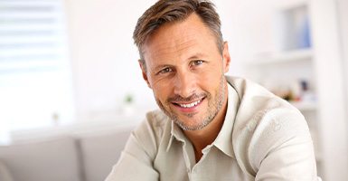 Smiling man in collared shirt sitting at home