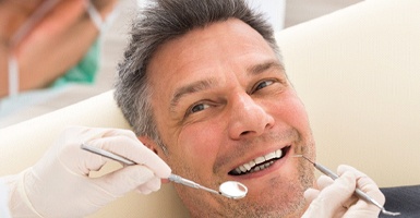 Smiling man with gray hair getting a consultation from a dentist  