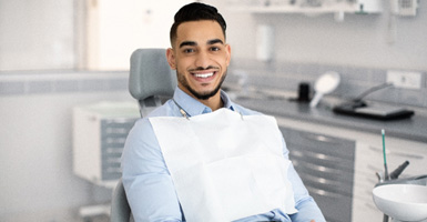 Male dental patient sitting in chair with hands folded