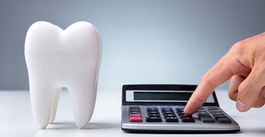 Tooth next to calculator, symbolizing cost of dental care
