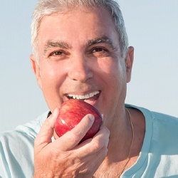 Man biting into red apple