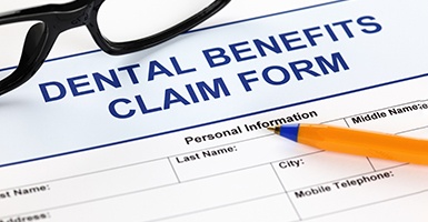 Dental insurance form with glasses and a pen