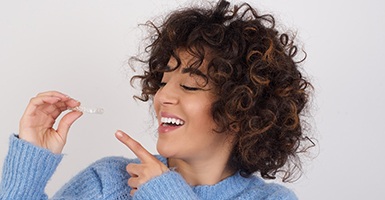 Woman smiling and pointing to her Invisalign aligner