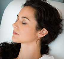 Dark haired woman laying down sleeping peacefully