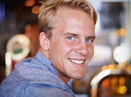 Male with blonde hair & blue shirt smiling