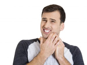 man in pain pressing jaw