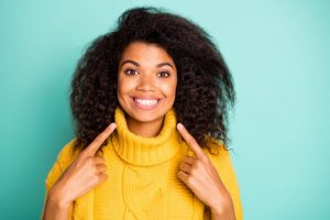 woman pointing at her smile after her cosmetic dentistry treatment