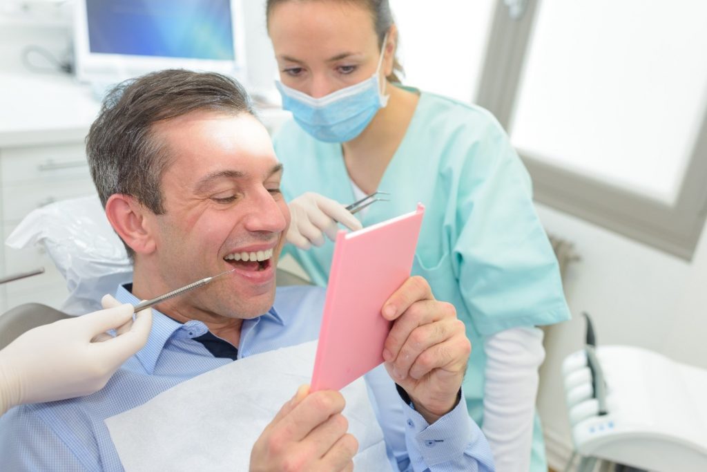 Patient looking at dental crown in dentist's mirror