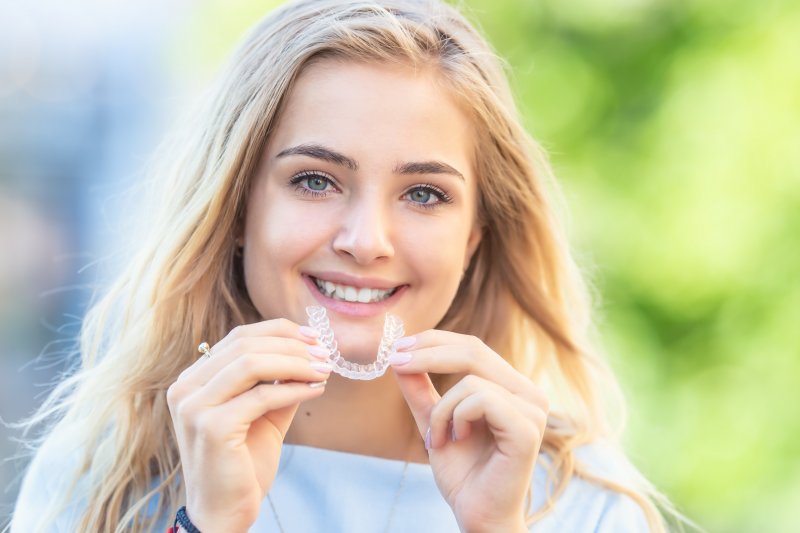 patient smiling and holding Invisalign aligner