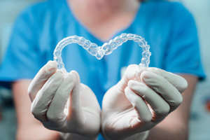 Woman holding two Invisalign aligners in a heart shape